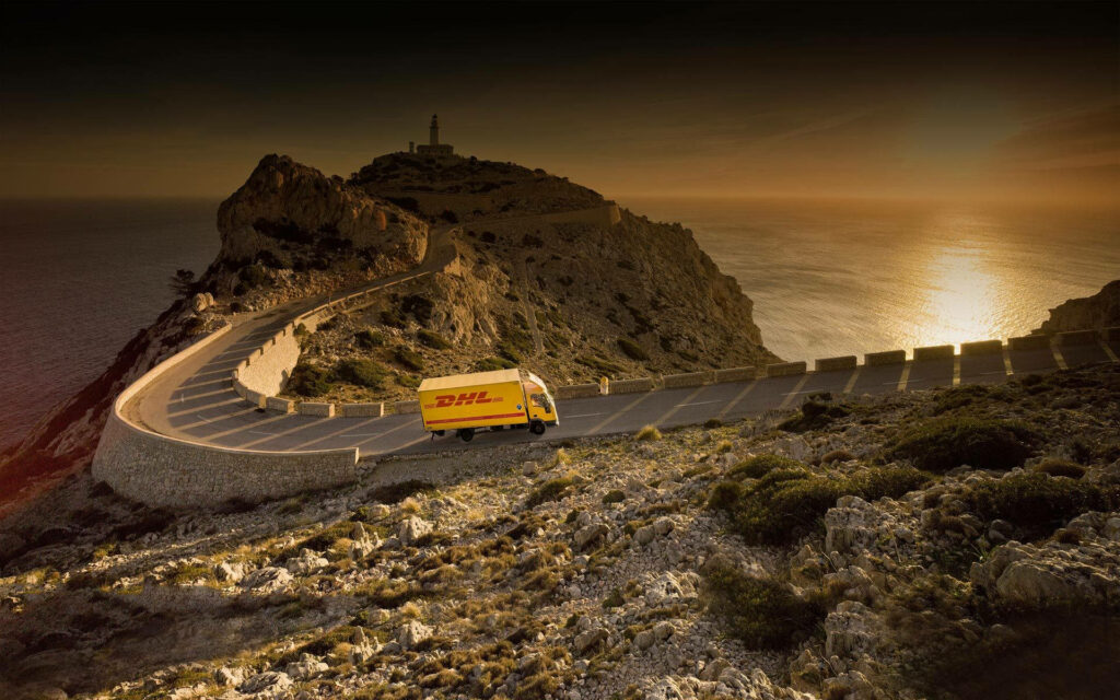DHL Express van on coastal road at sunset with cliffs and calm sea showcasing speed and reliability Wallpaper