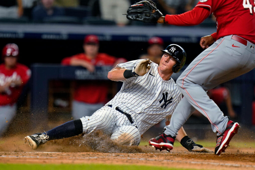 DJ LeMahieu slides into home plate in Yankees pinstripes on vibrant baseball field during intense game Wallpaper
