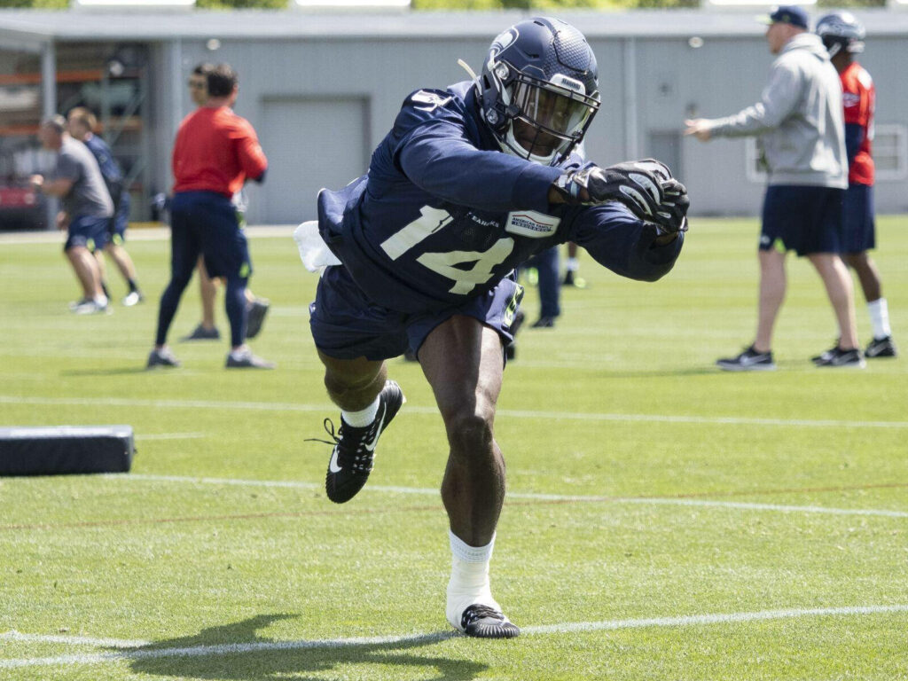DK Metcalf in blue Seahawks uniform mid-action on green turf showcasing athleticism wallpaper