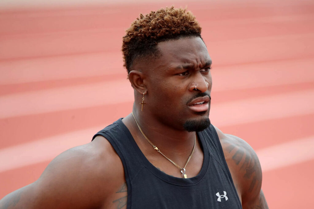 DK Metcalf on outdoor track in black tank top showing athletic build and focused look Wallpaper