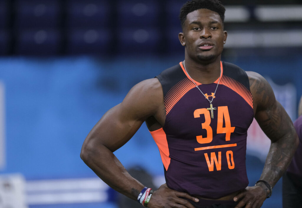 DK Metcalf in vibrant sports gear posing confidently with muscular physique in stadium background Wallpaper