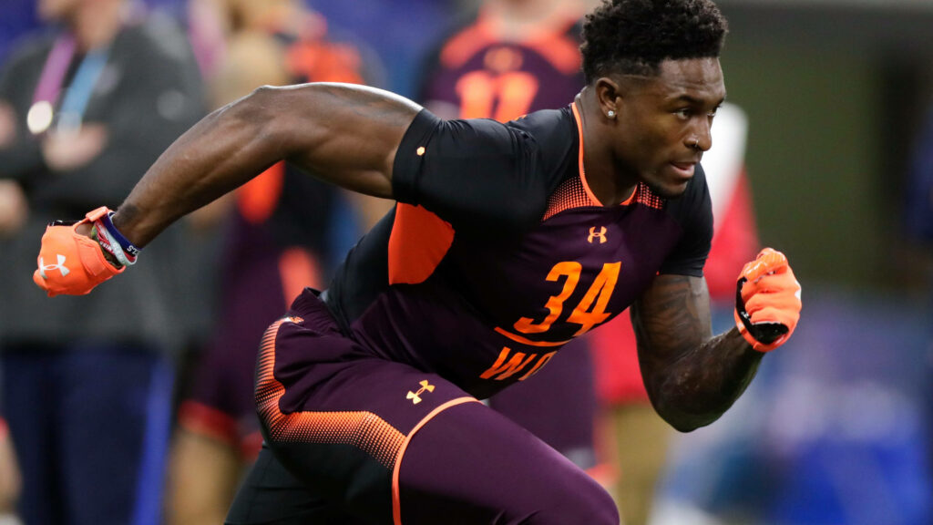 DK Metcalf sprinting in black and orange number 34 uniform showcasing power and focus Wallpaper