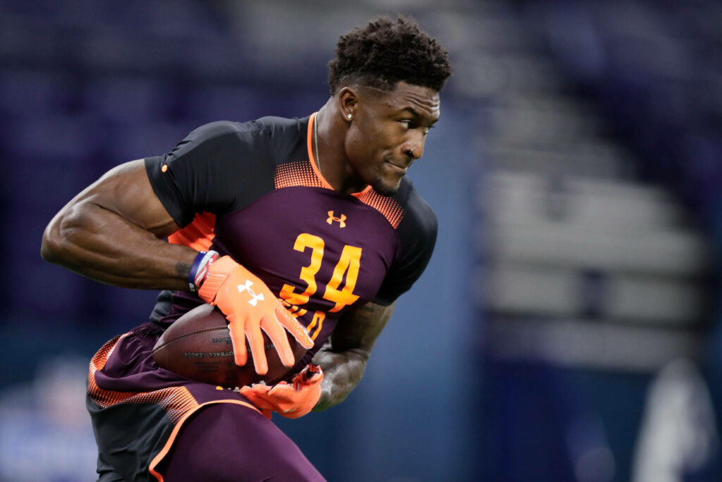 DK Metcalf in number 34 uniform running with football showing speed determination in stadium Wallpaper