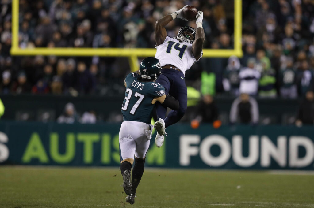 DK Metcalf leaps high for a powerful football catch in vibrant stadium action wallpaper background