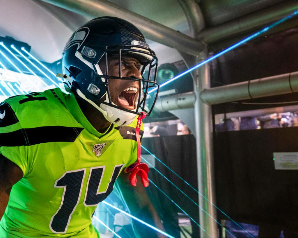 DK Metcalf mid-scream in neon green Seahawks jersey with blue lasers and dynamic shadows wallpaper