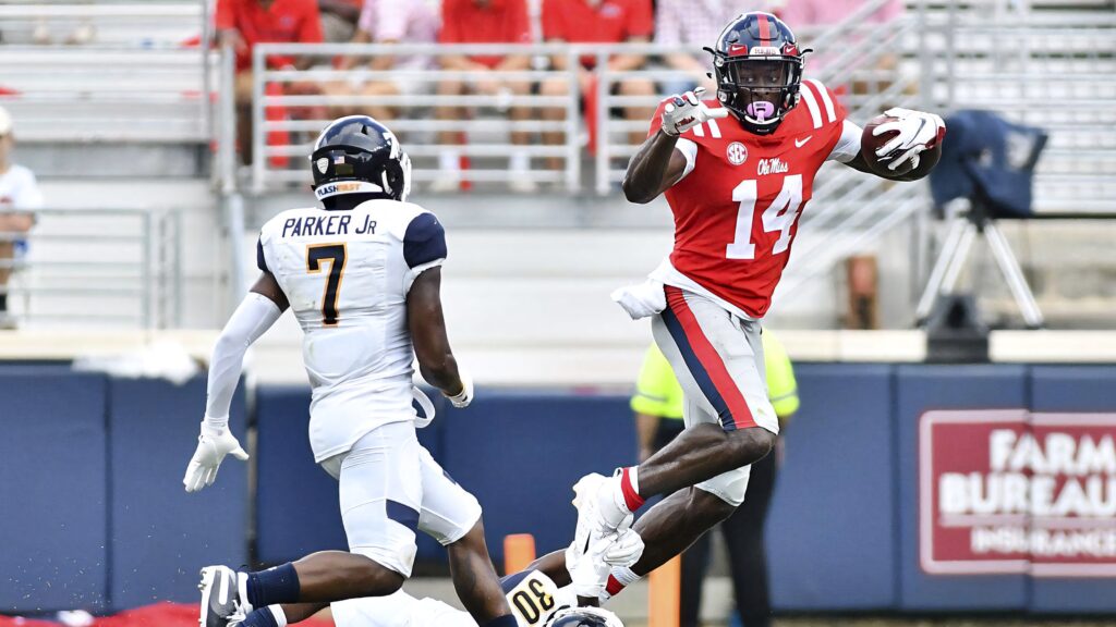 DK Metcalf in red Ole Miss uniform catching football as defender Parker Jr closes in at stadium game Wallpaper