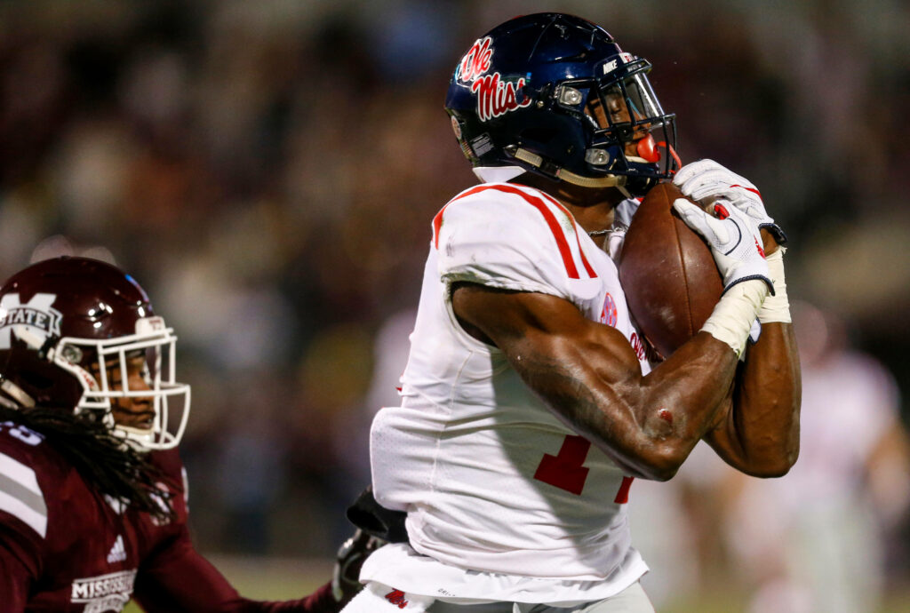 DK Metcalf in Ole Miss uniform mid-game holding football showing focus and athleticism Wallpaper