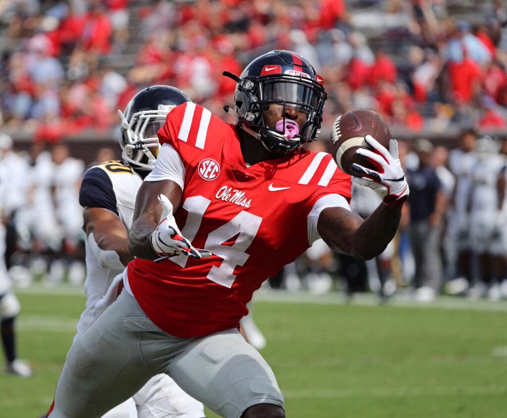 DK Metcalf Ole Miss football action reaching for pass vibrant red white uniform stadium backdrop Wallpaper