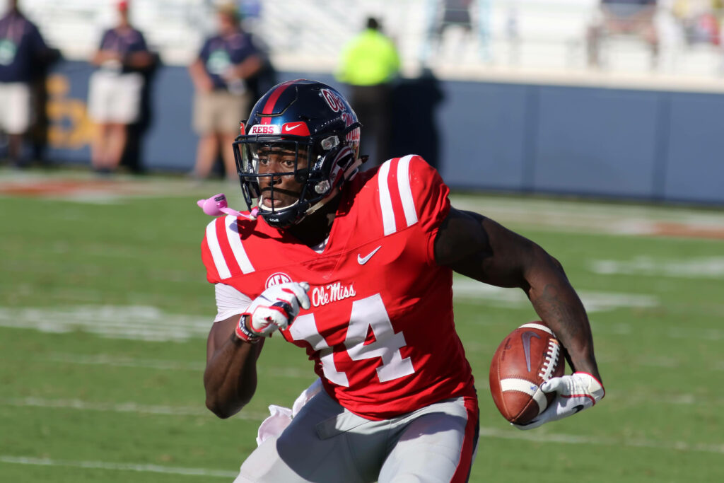 DK Metcalf in red Ole Miss jersey number 14 showing athletic focus on football field action Wallpaper