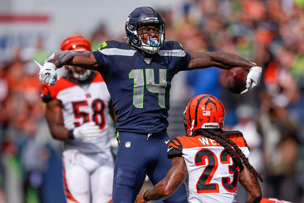 DK Metcalf leaps powerfully over Bengals defender showcasing Seattle Seahawks NFL action moment Wallpaper