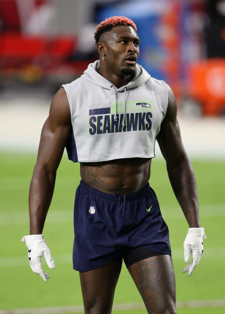 DK Metcalf in Seahawks sleeveless crop top and shorts showing muscular athletic build on field Wallpaper