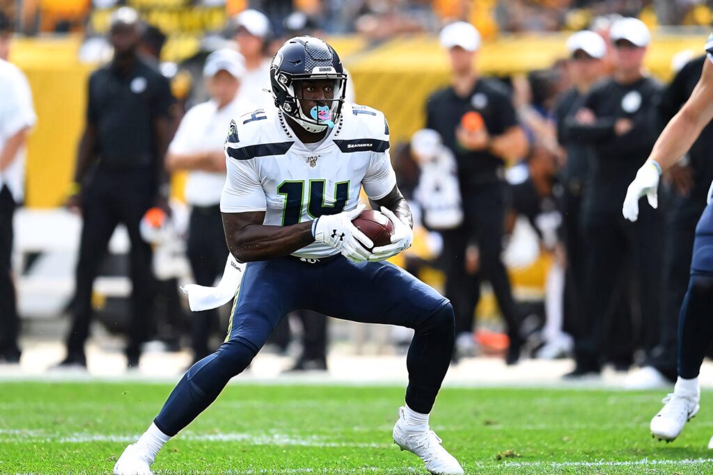 DK Metcalf in Seattle Seahawks uniform prepares to catch ball on vibrant green football field wallpaper