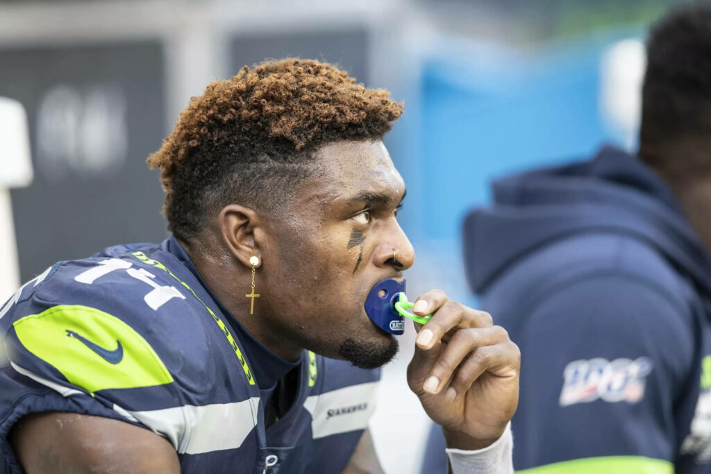 DK Metcalf in Seattle Seahawks uniform holding mouthpiece showing intense focus and athleticism Wallpaper