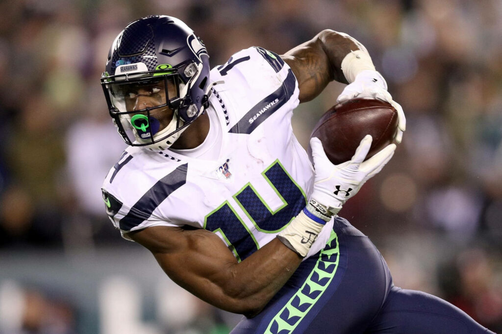 DK Metcalf in Seattle Seahawks uniform charges forward in vibrant NFL stadium action wallpaper