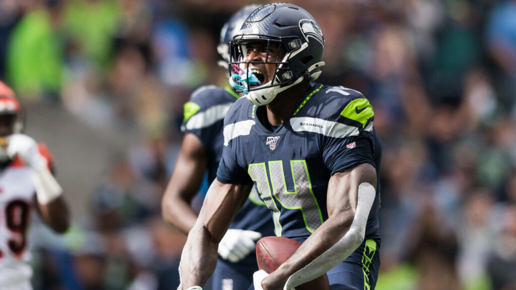 DK Metcalf Seattle Seahawks wide receiver action shot with blue mouthguard and stadium background Wallpaper