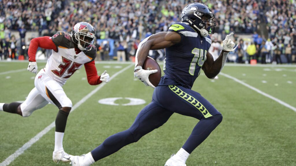 DK Metcalf sprinting in Seattle Seahawks uniform with vibrant crowd background NFL action wallpaper