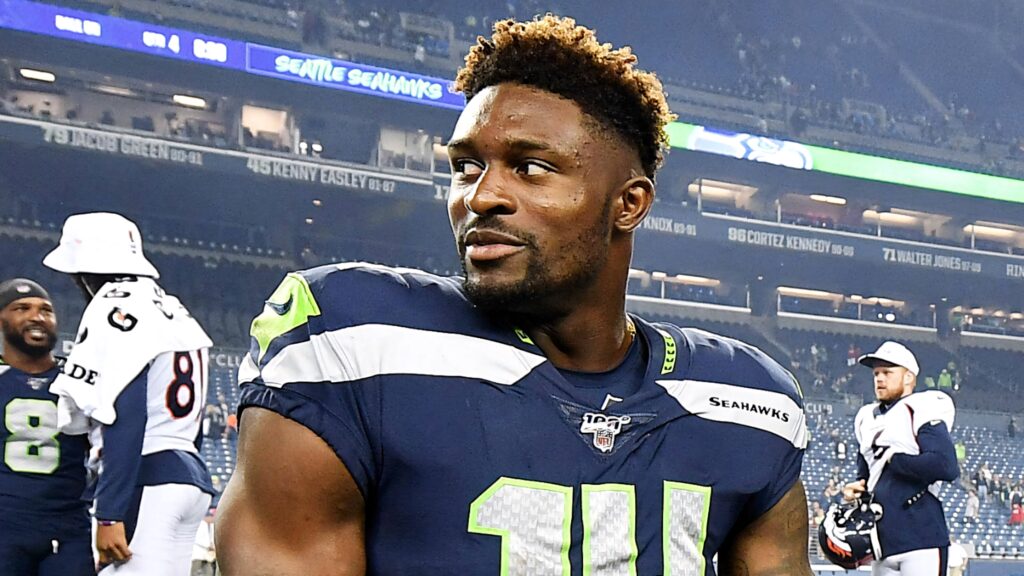 DK Metcalf in Seattle Seahawks uniform side glance under stadium lights on game night wallpaper