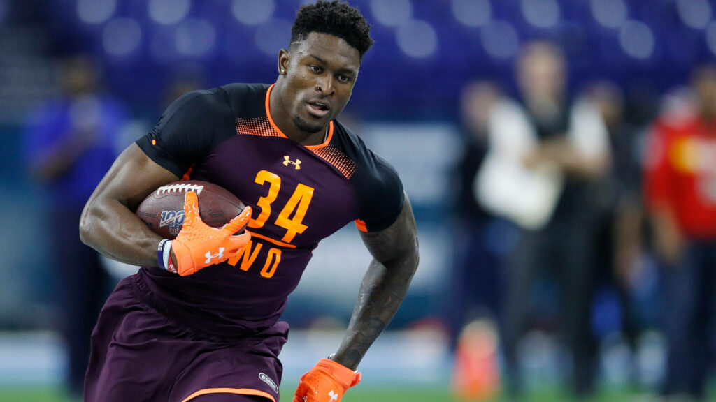 DK Metcalf in violet NFL jersey gripping football with intense focus dynamic stadium background Wallpaper