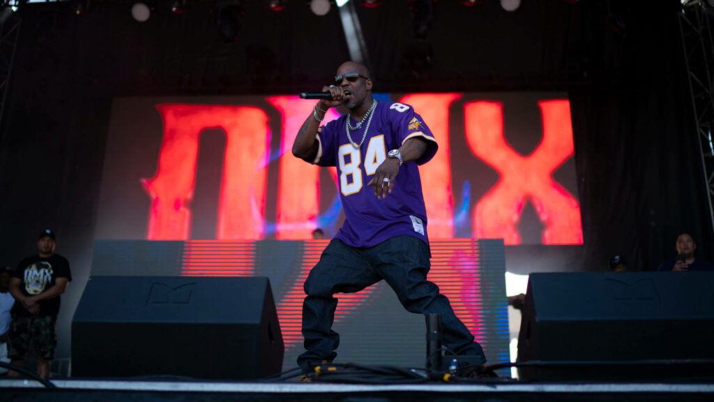 DMX performing live on stage in purple jersey with dramatic red backdrop and vibrant concert lighting Wallpaper