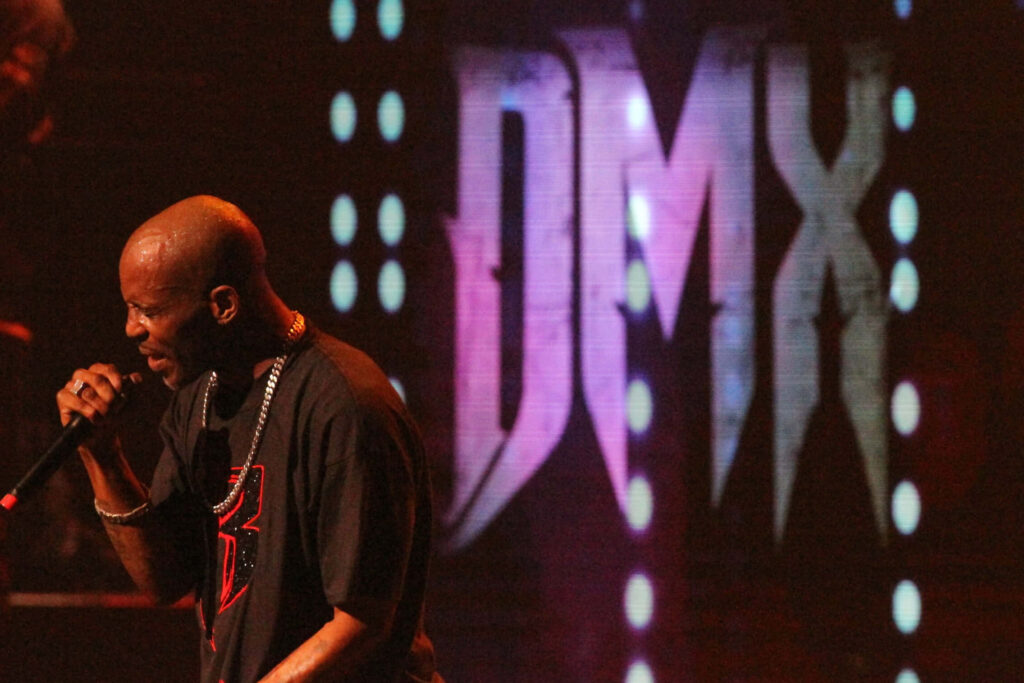 DMX live performance wallpaper with purple illuminated DMX letters and intense stage presence