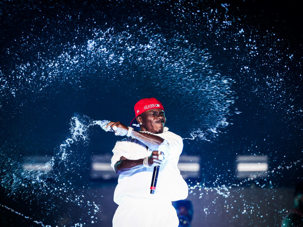 DaBaby performing at Rolling Loud Festival in white outfit and red hat with water splashing background Wallpaper