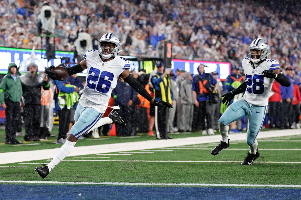 Dallas Cowboys DaRon Bland intercepts pass from Saquon Barkley sprinting on football field Wallpaper