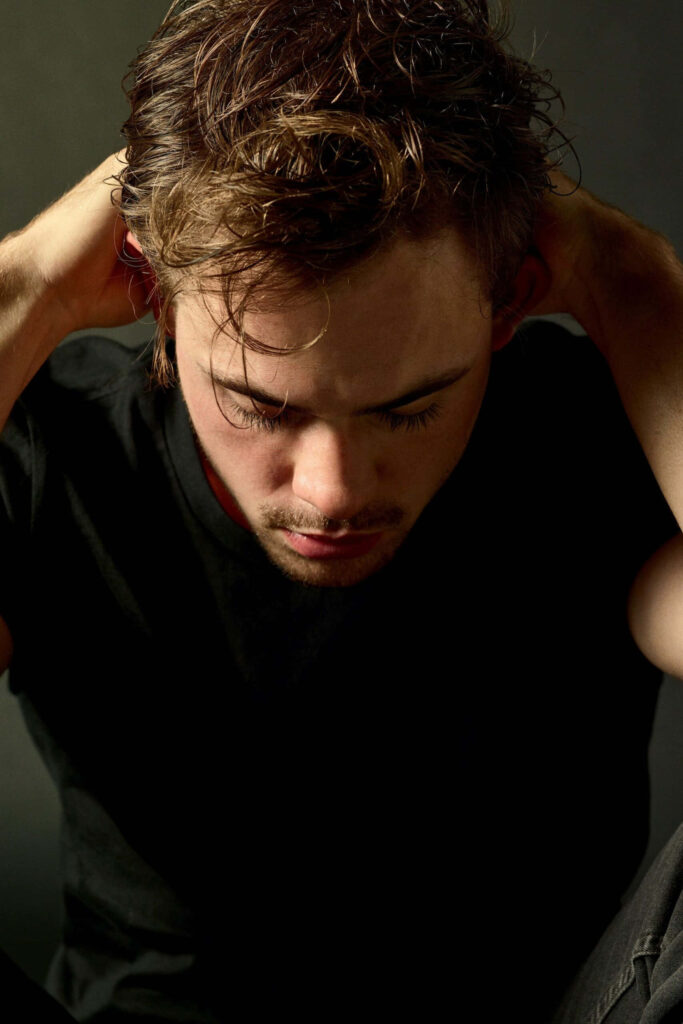 Dacre Montgomery contemplative close-up portrait with dramatic lighting and moody muted tones wallpaper