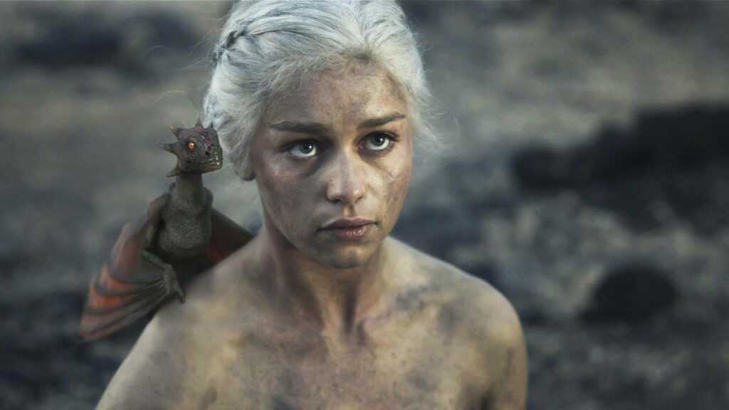 Daenerys Targaryen with baby dragon on shoulder in smoky rugged landscape wallpaper background