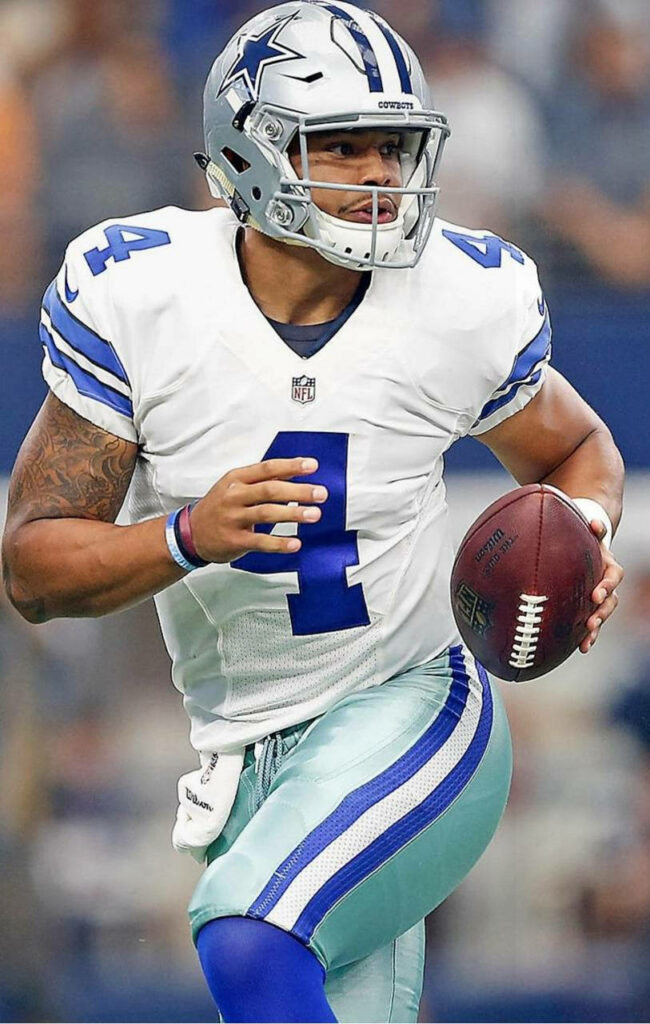 Dak Prescott in Dallas Cowboys uniform poised to throw football showing focus and athleticism Wallpaper