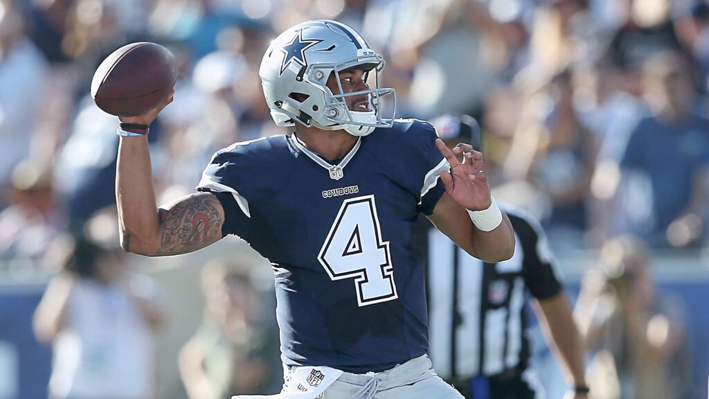 Dak Prescott in Dallas Cowboys uniform number 4 throwing a forward pass in vibrant NFL stadium Wallpaper