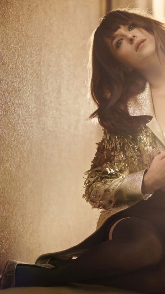 Dakota Johnson glamorous wallpaper in gold fringed jacket soft warm lighting high fashion style