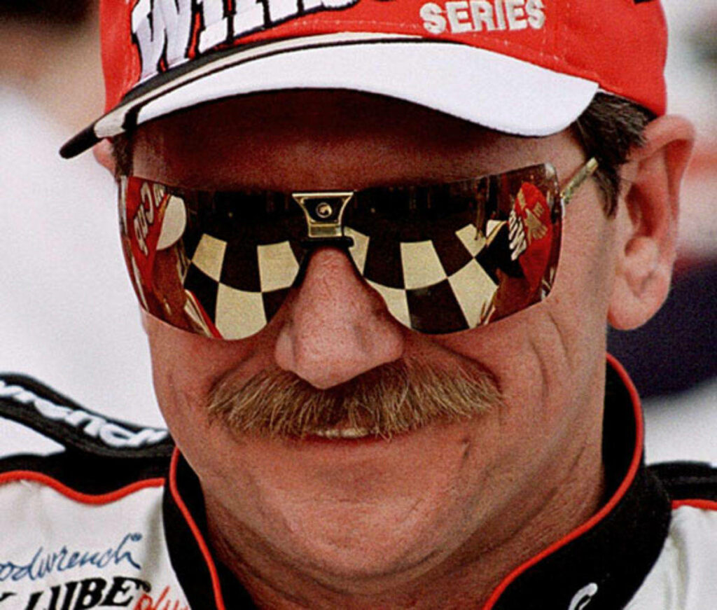Close-up of Dale Earnhardt in racing gear with signature mustache and checkered flag sunglasses Wallpaper