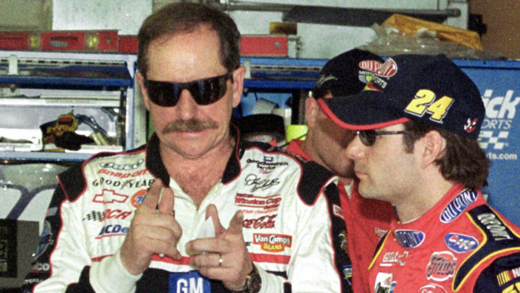 Dale Earnhardt in racing suit and sunglasses with fellow driver in garage NASCAR wallpaper