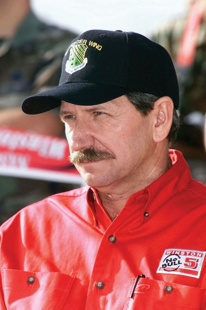 Dale Earnhardt portrait wallpaper in red shirt black cap sharp focus iconic mustache motorsports legend