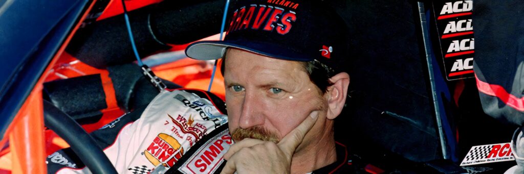Dale Earnhardt in white racing suit and black Braves cap focused in classic motorsport race car Wallpaper