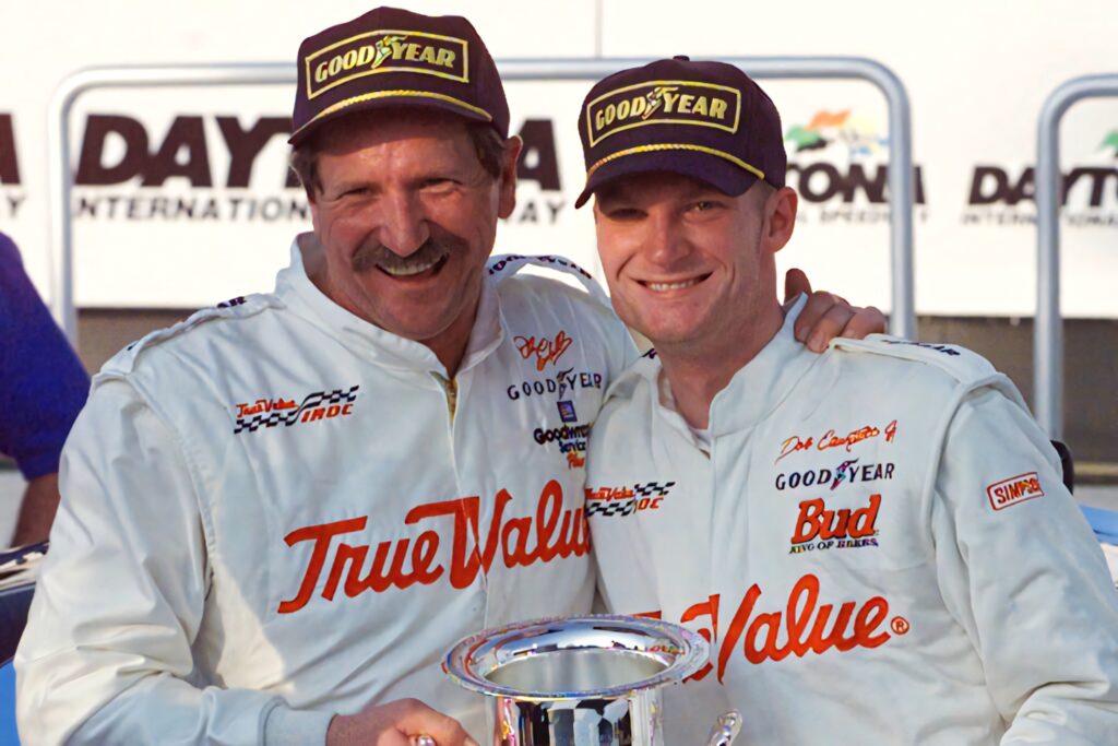 Dale Earnhardt Sr and Jr smiling in racing suits and Goodyear caps vibrant NASCAR wallpaper