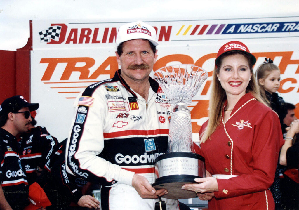 Dale Earnhardt in Goodwrench racing suit holding crystal trophy at Darlington Raceway victory celebration Wallpaper