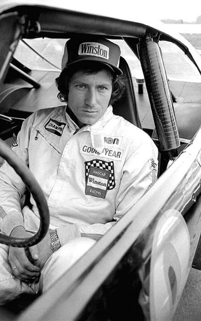 Monochrome wallpaper of Dale Earnhardt in vintage racing suit seated in classic race car focus eyes