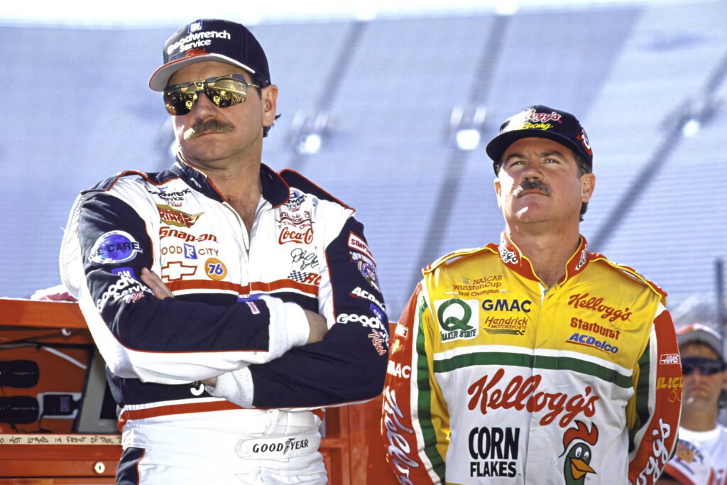 Dale Earnhardt and Terry Labonte in classic NASCAR suits with bold logos on raceway backdrop Wallpaper