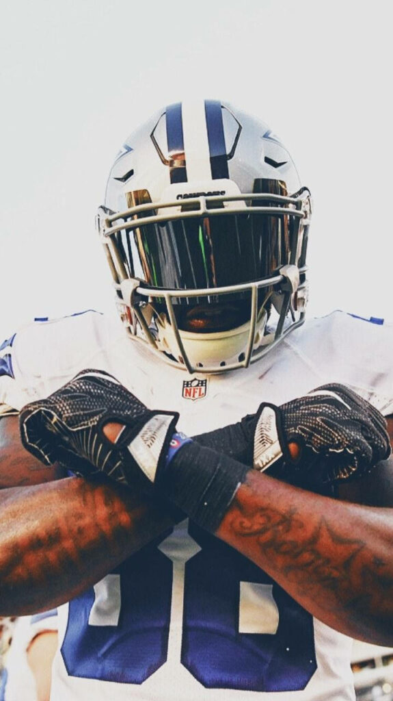 Dallas Cowboys football player in full uniform with crossed arms showcasing team colors wallpaper
