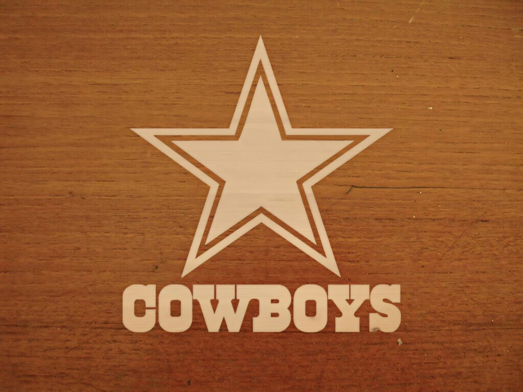 Dallas Cowboys logo with bold star and block text engraved in light wood on orange wood background Wallpaper
