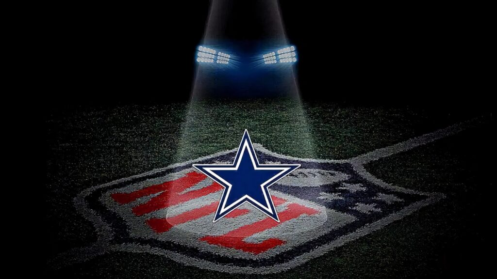 Illuminated Dallas Cowboys star above NFL shield on textured football field stadium background Wallpaper