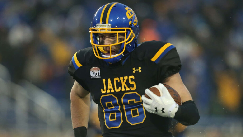 Dallas Goedert 86 in black blue Jacks uniform catches football in action blurred stadium background Wallpaper