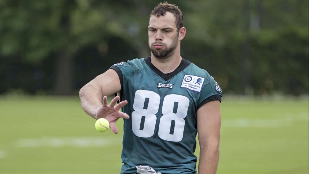 Dallas Goedert in teal Eagles jersey catches tennis ball during focused outdoor practice session Wallpaper