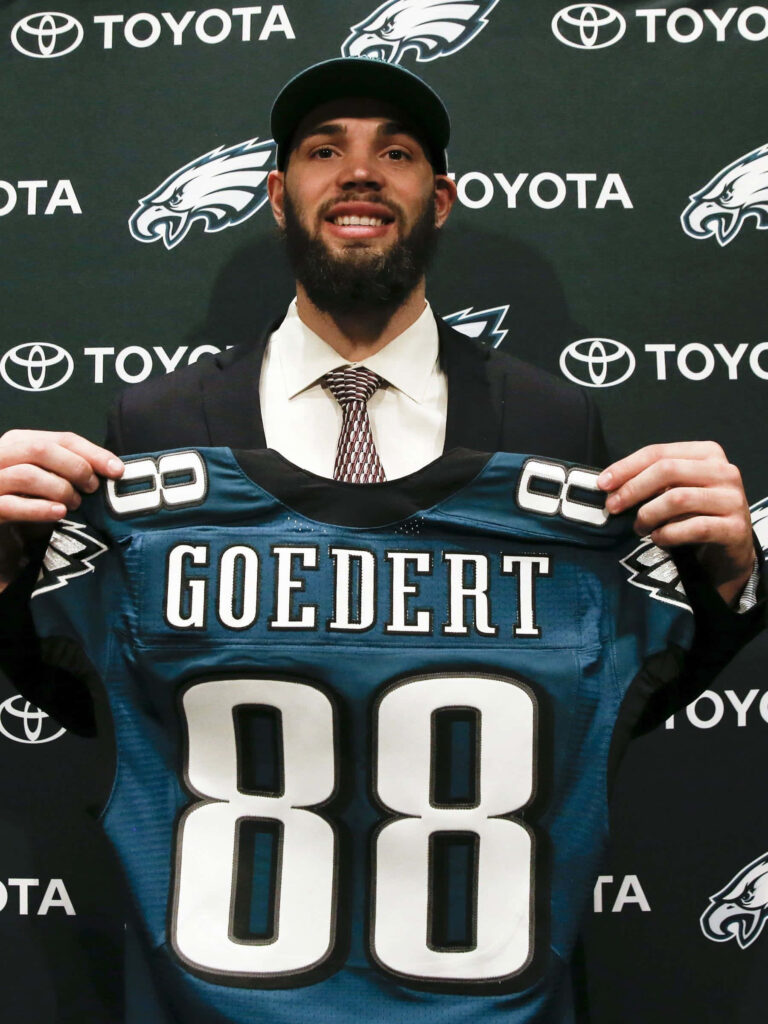 Dallas Goedert smiling holding Philadelphia Eagles jersey number 88 at official NFL signing event Wallpaper
