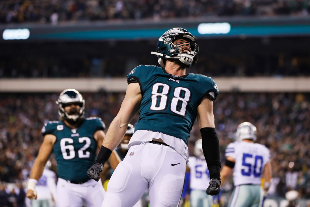 Dallas Goedert #88 Eagles celebrates on field with crowd and teammates during intense NFL game Wallpaper