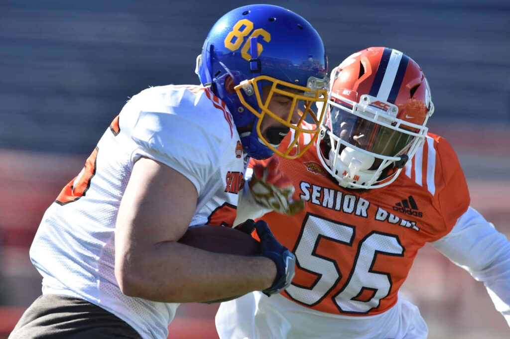 Dallas Goedert in blue and yellow helmet practicing football at Senior Bowl against orange opponent Wallpaper