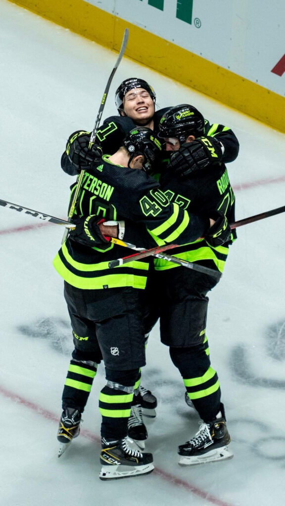 Dallas Stars hockey team celebrating victory with Jason Robertson in black neon green uniforms on ice Wallpaper