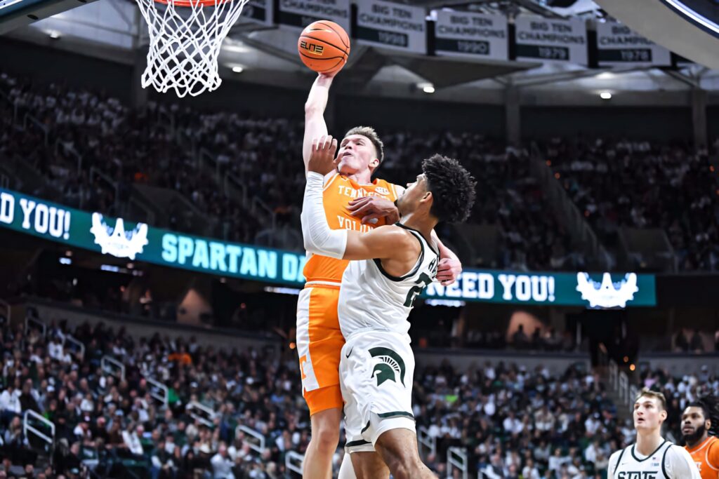 Dalton Knecht basketball layup in Tennessee uniform vs Michigan State defender in packed stadium Wallpaper