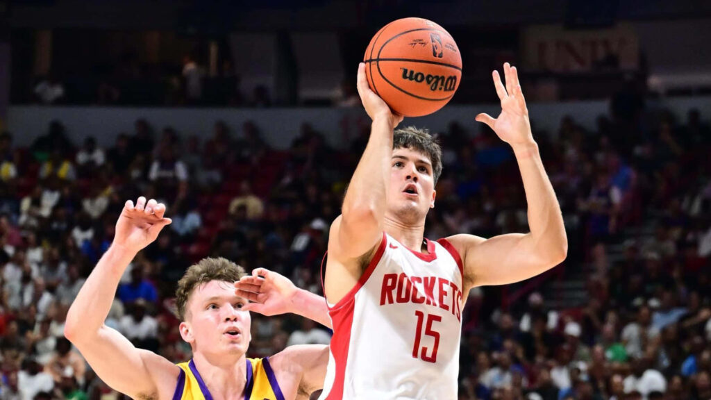 Dalton Knecht in red Rockets jersey jumps to shoot basketball over defender in packed arena Wallpaper